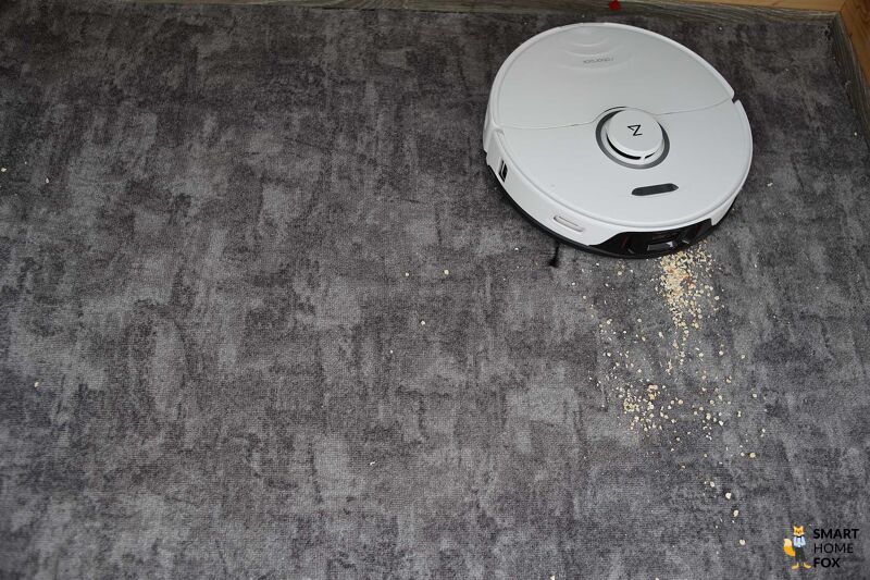 Roborock S8 Pro Ultra reinigt Haferflocken beim Saugtest auf einem Teppichboden.